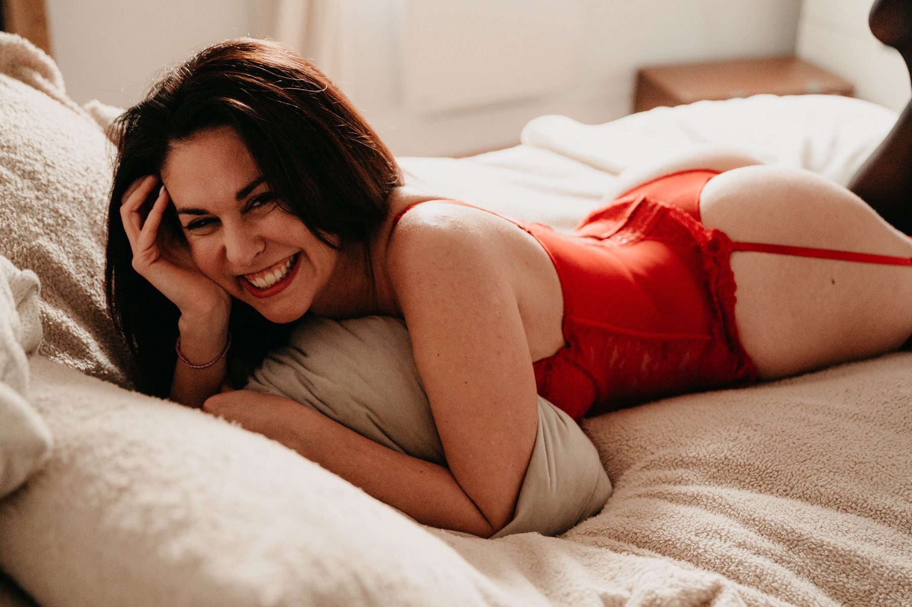 Femme allongée sur le lit, sourire chaleureux, instant de détente